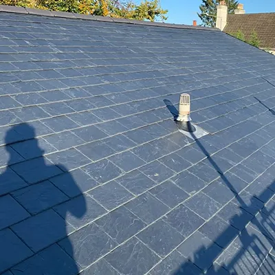 A person standing on a roof with a shadow on it.